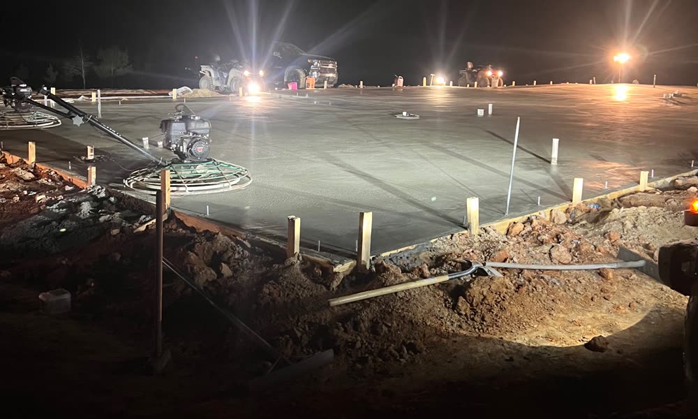 Freshly poured slab being finished under lights on a Pokie's night pour